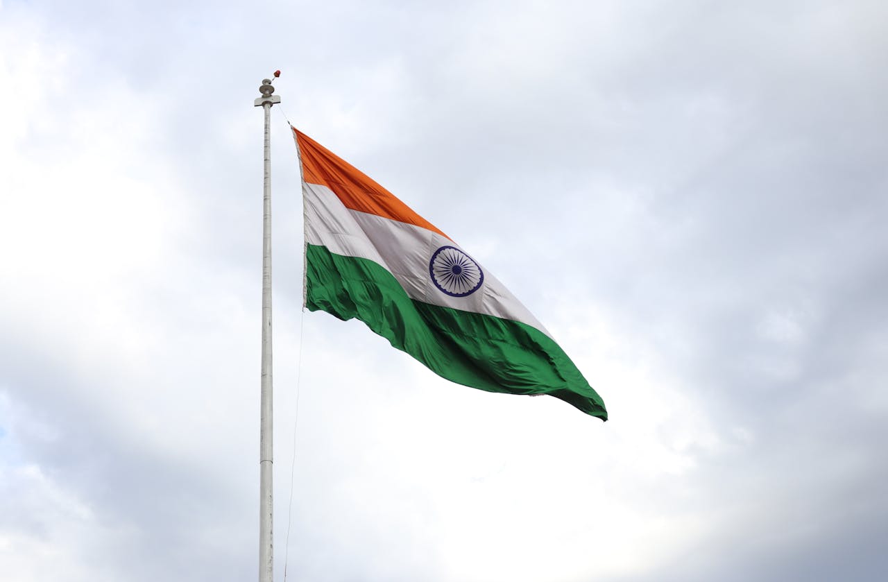 The Flag of India on a Flagpole under a Cloudy Sky